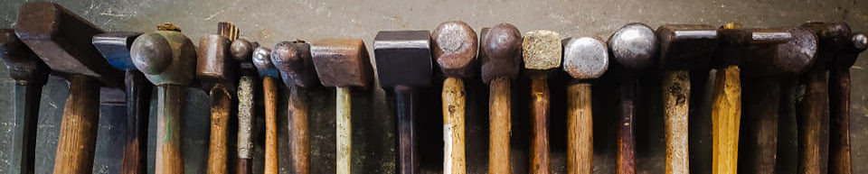 Collection of various hammers arranged in a row on a textured surface